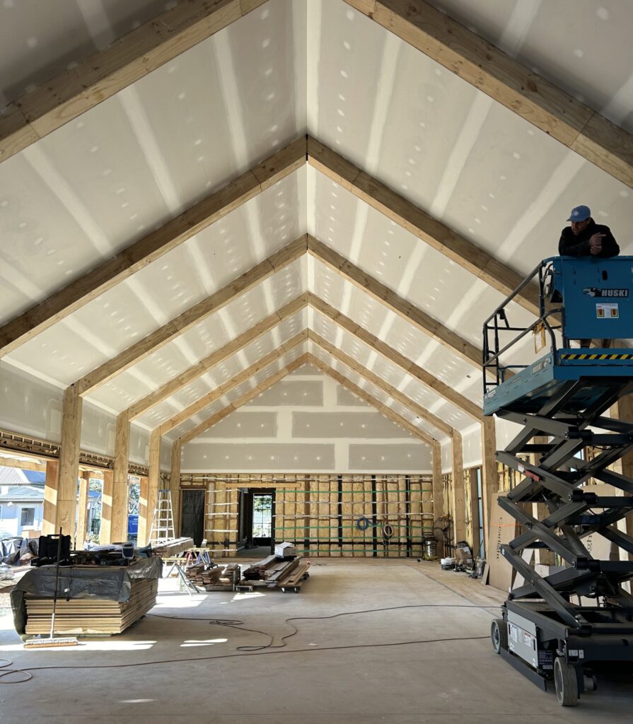 Home Electrician operating a scissor lift installing electrical systems in a new build